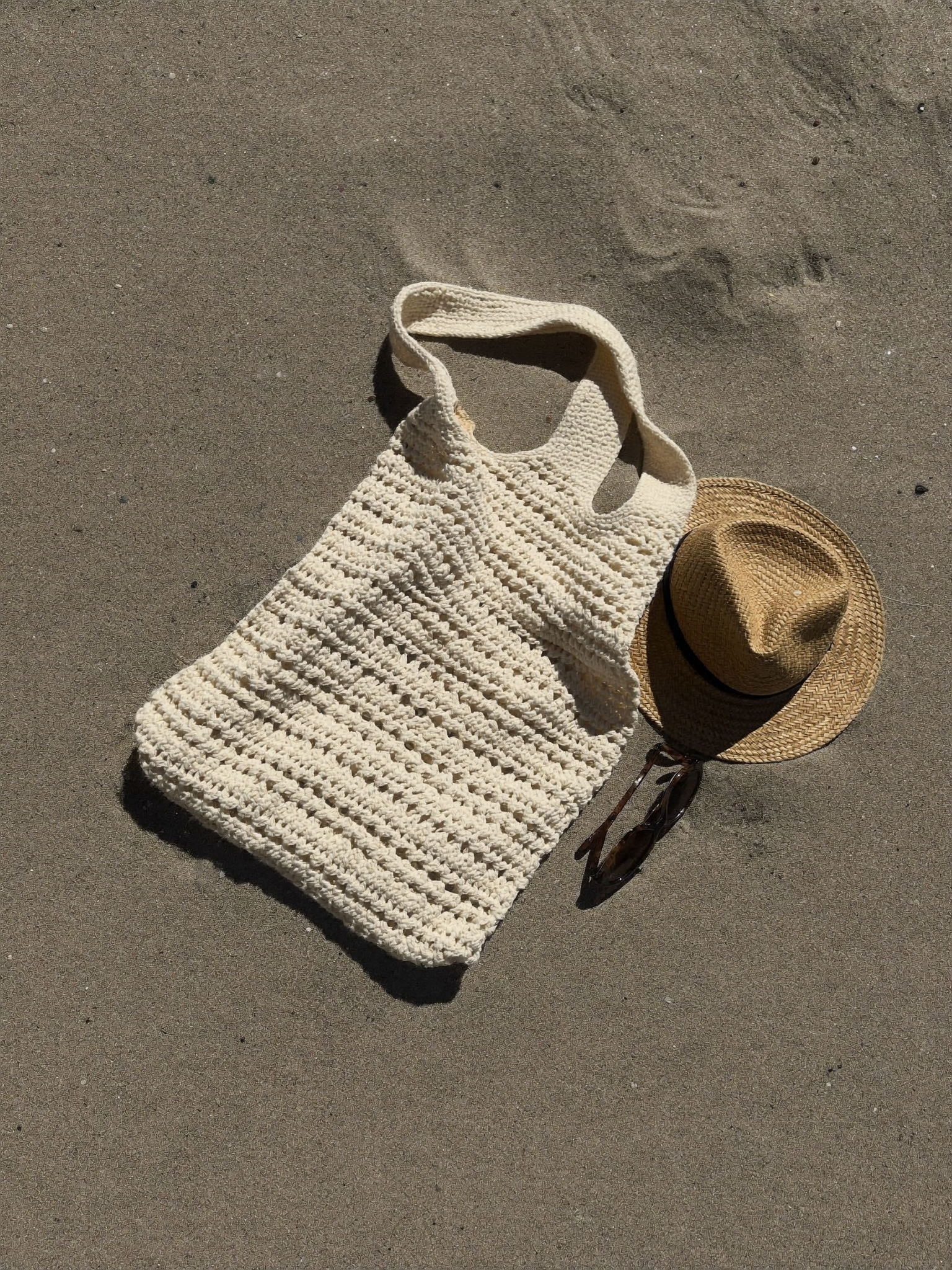 Grand tote bag de plage au crochet en coton écru sur le sable