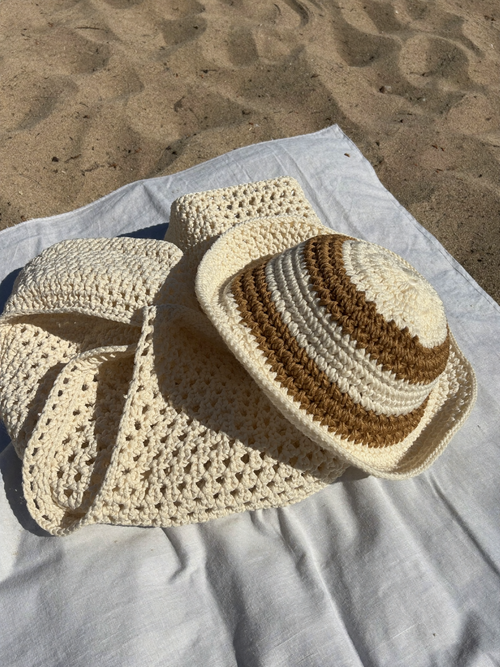 Coffret plage : cabas au crochet écru et bob rayé sur le sable