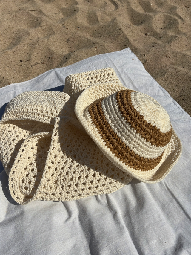 Coffret plage : cabas au crochet écru et bob rayé sur le sable